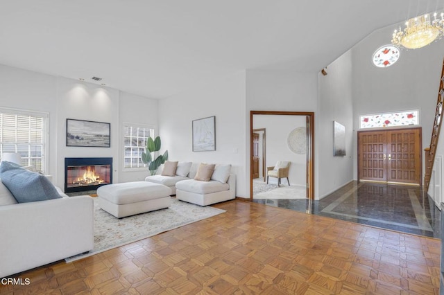 living room featuring a glass covered fireplace, an inviting chandelier, and a towering ceiling