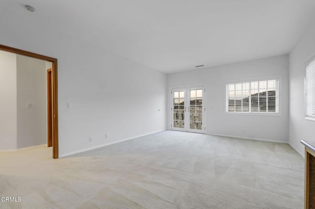 unfurnished room with french doors, baseboards, and light colored carpet