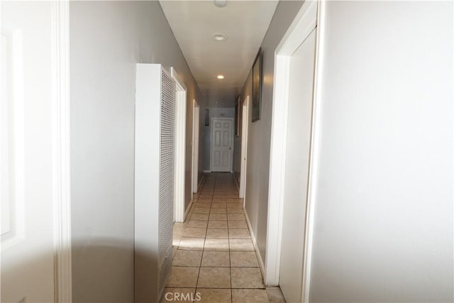 hallway featuring baseboards, light tile patterned flooring, and recessed lighting