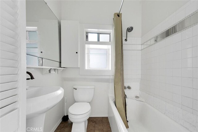 full bath with washtub / shower combination, baseboards, toilet, tile patterned floors, and a sink