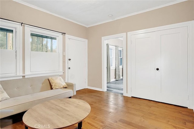 living room featuring baseboards, a wealth of natural light, crown molding, and light wood-type flooring