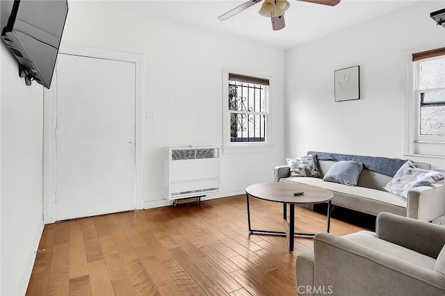 living room featuring heating unit, wood finished floors, and a ceiling fan