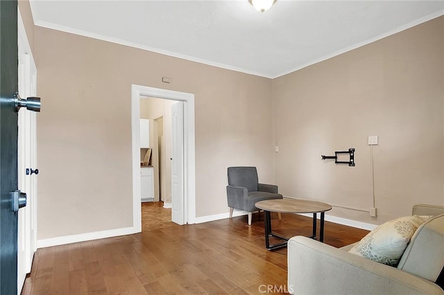 sitting room with crown molding, baseboards, and wood finished floors