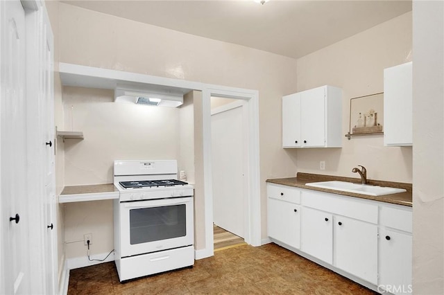 kitchen with range hood, white gas stove, dark countertops, white cabinetry, and a sink