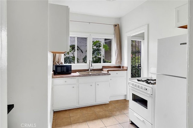 kitchen with white cabinets, a sink, light tile patterned floors, and white appliances
