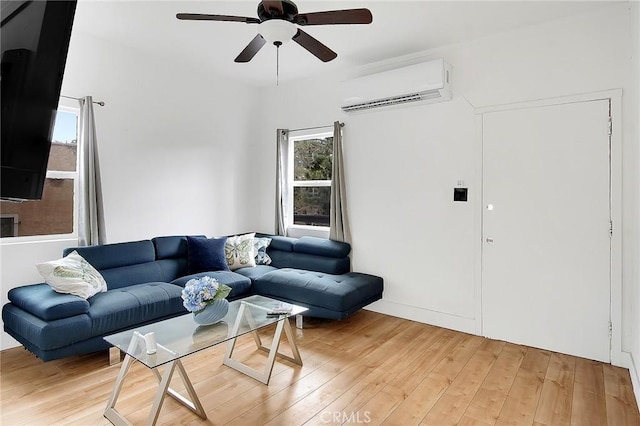living area featuring a ceiling fan, a wall mounted air conditioner, and light wood-style floors