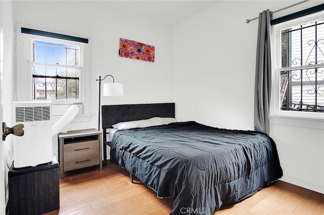 bedroom featuring light wood-style floors, baseboards, and multiple windows