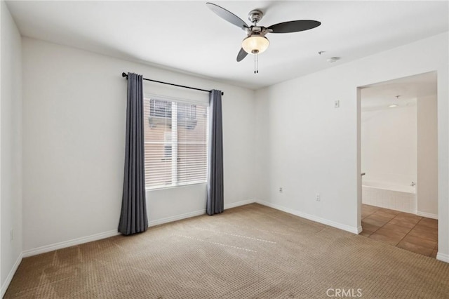 carpeted empty room with tile patterned floors, baseboards, and ceiling fan