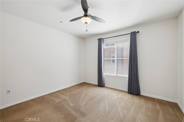 carpeted spare room featuring a ceiling fan and baseboards