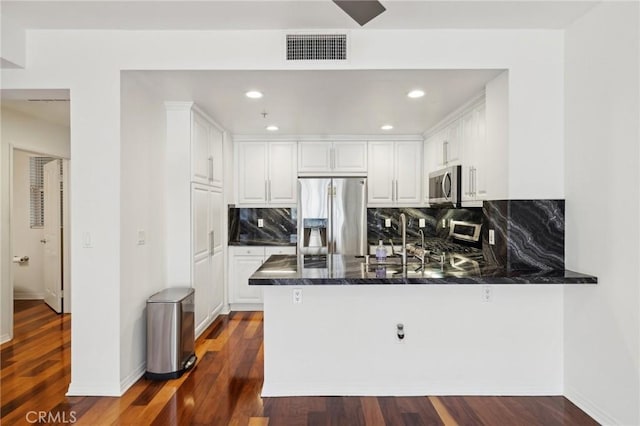 kitchen with visible vents, dark wood finished floors, a peninsula, appliances with stainless steel finishes, and white cabinetry