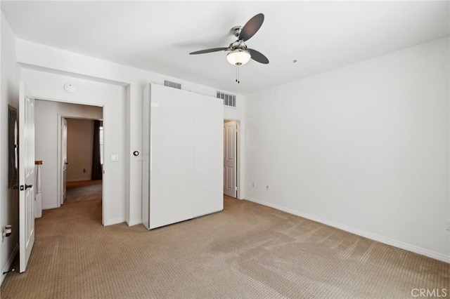 unfurnished bedroom with visible vents, baseboards, light colored carpet, and ceiling fan