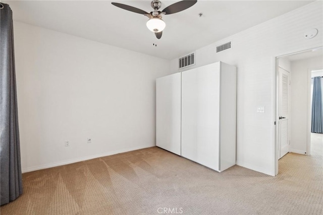 unfurnished bedroom with visible vents, baseboards, light colored carpet, and ceiling fan