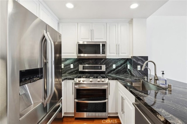 kitchen featuring backsplash, appliances with stainless steel finishes, white cabinetry, and a sink