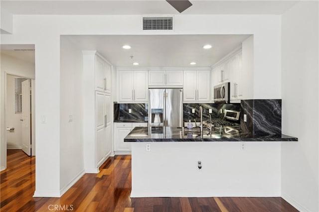 kitchen featuring visible vents, a peninsula, dark wood-style flooring, appliances with stainless steel finishes, and white cabinetry