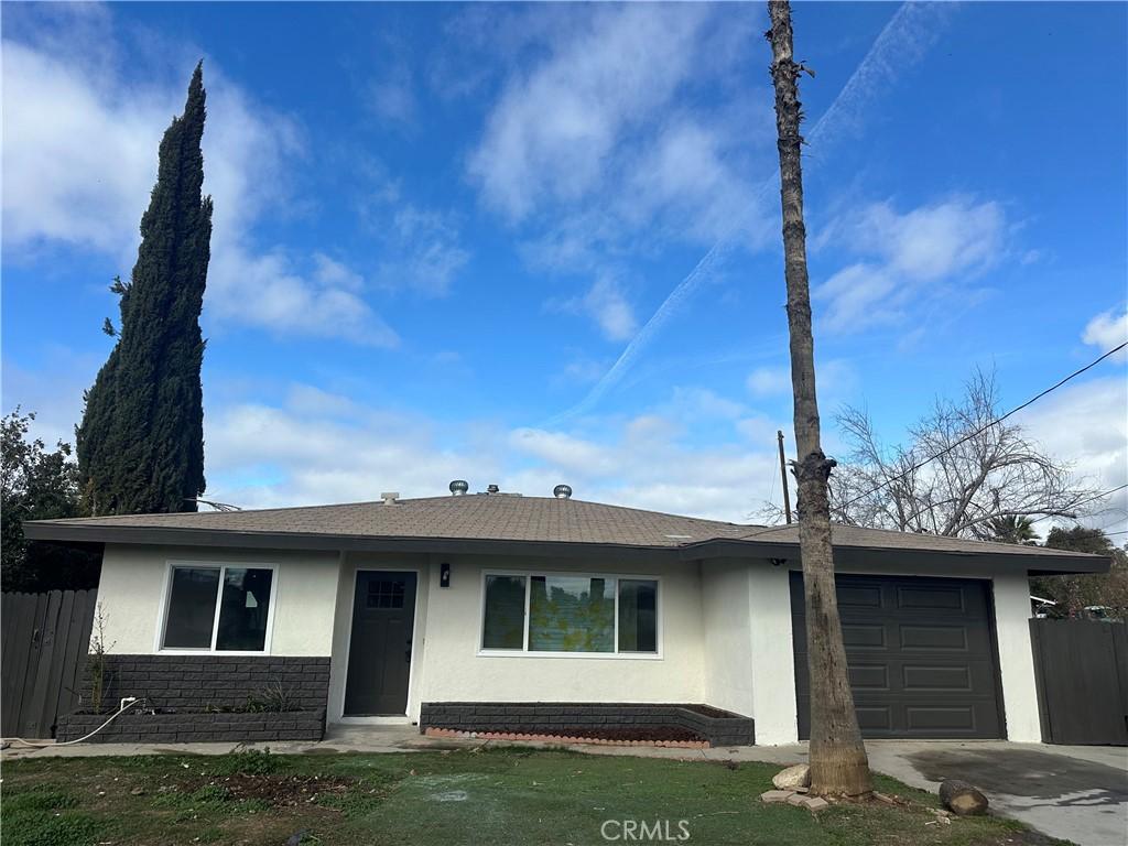 single story home with fence, stucco siding, driveway, stone siding, and an attached garage