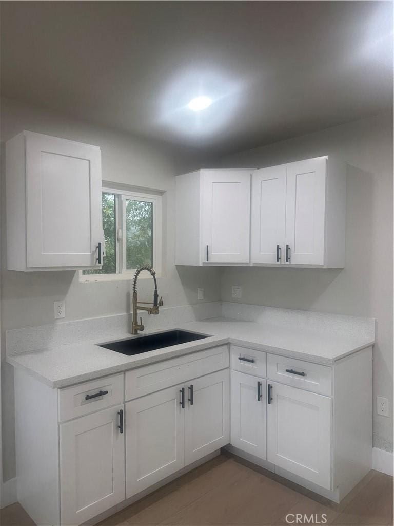 kitchen with light countertops, white cabinets, and a sink