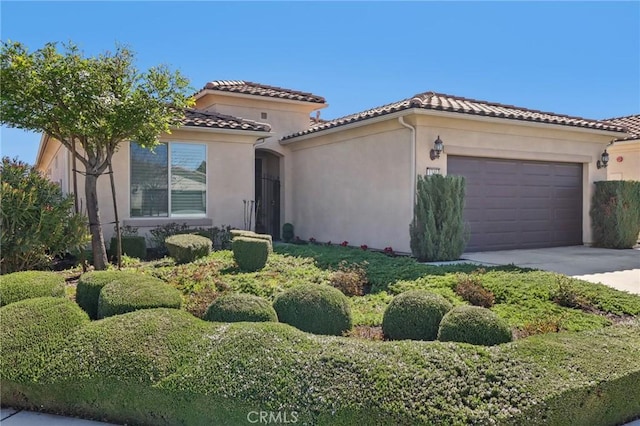 mediterranean / spanish house with stucco siding, driveway, a tile roof, and a garage