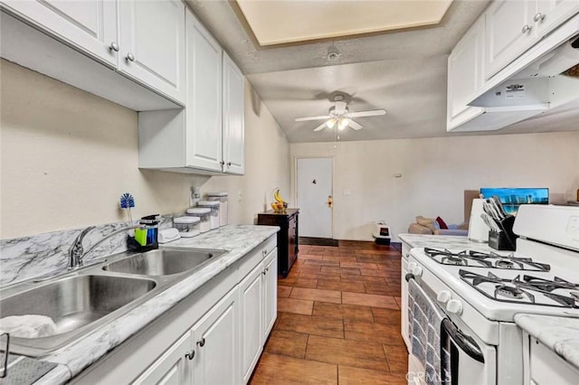 kitchen featuring under cabinet range hood, a sink, white cabinetry, and white gas range oven