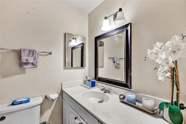 bathroom featuring vanity, toilet, and a textured wall