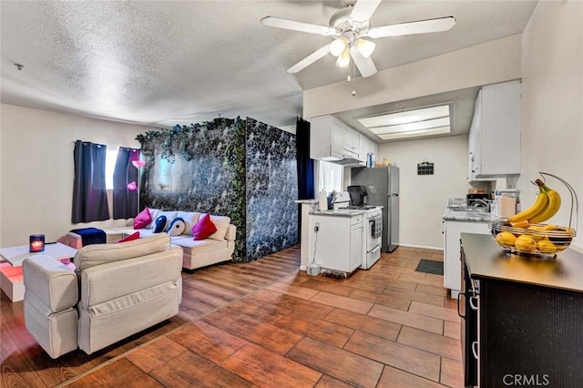 living area with a textured ceiling, light wood-style flooring, and a ceiling fan