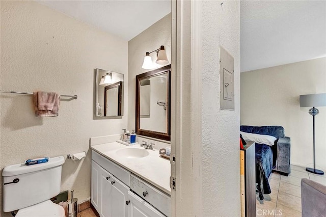 bathroom with tile patterned flooring, toilet, vanity, and a textured wall