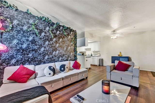 living room with ceiling fan, baseboards, a textured ceiling, and wood finished floors