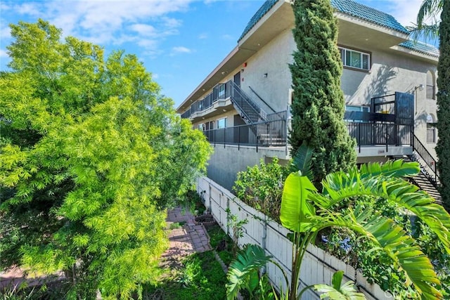 view of property exterior with stucco siding and fence