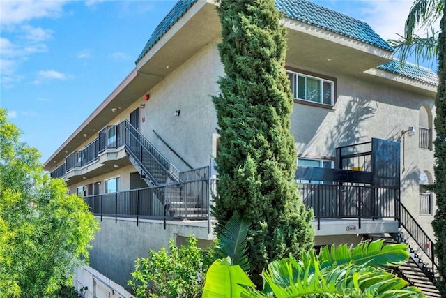 view of side of home featuring a tile roof and stucco siding