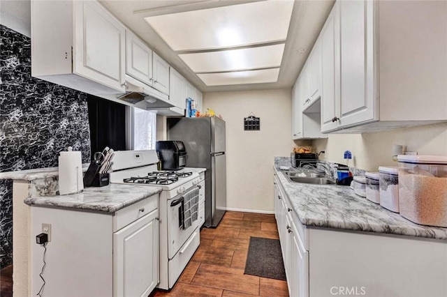 kitchen featuring under cabinet range hood, a sink, white cabinetry, and white gas range oven