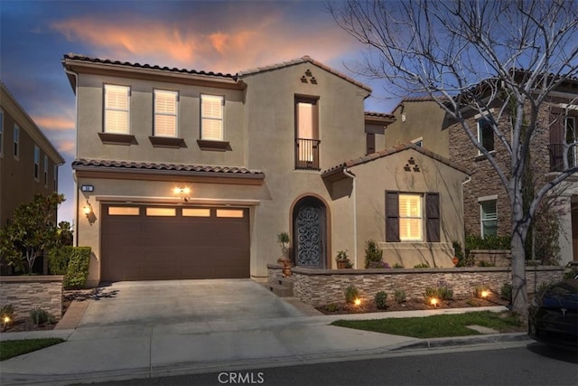 mediterranean / spanish-style house featuring stucco siding, a tiled roof, concrete driveway, and a garage