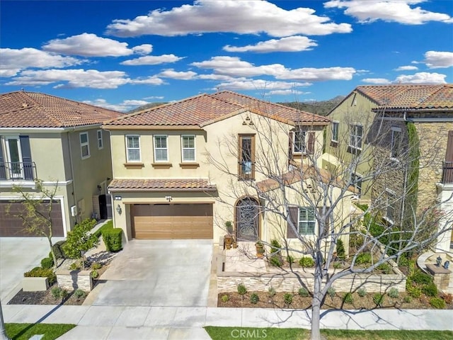 mediterranean / spanish house with stucco siding, a garage, driveway, and a tiled roof