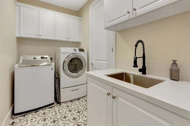 laundry room with cabinet space, light tile patterned floors, washing machine and dryer, and a sink