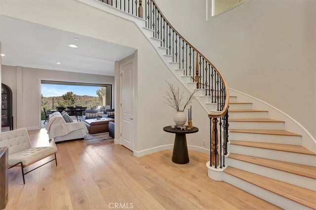 stairs featuring recessed lighting, baseboards, wood finished floors, and a towering ceiling