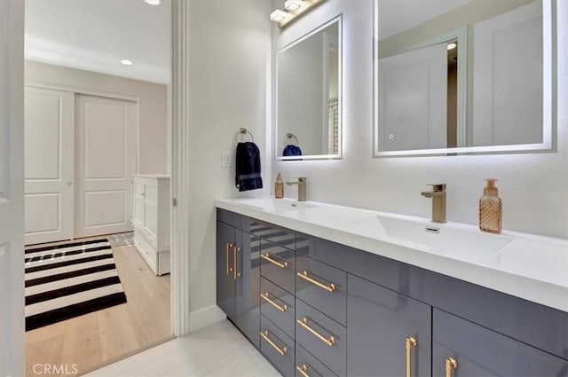 bathroom with double vanity, recessed lighting, wood finished floors, and a sink