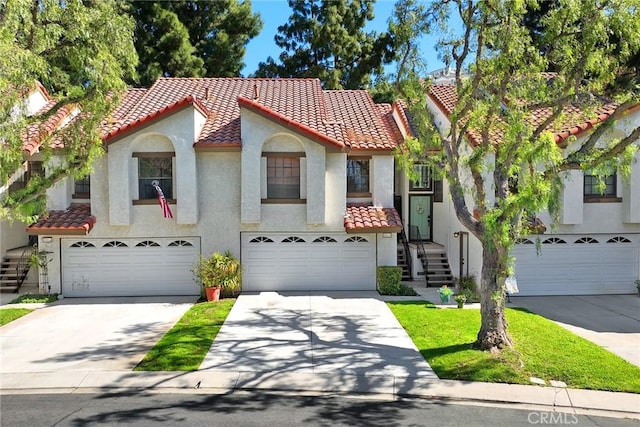 mediterranean / spanish house featuring stucco siding, concrete driveway, and a tile roof