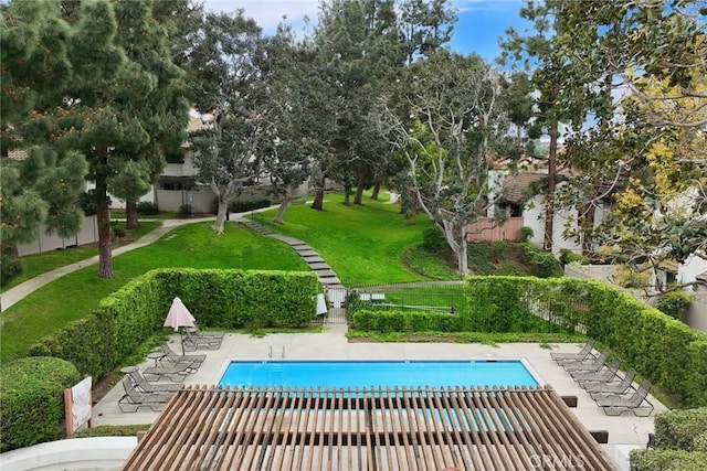 community pool with fence, a lawn, and a patio area