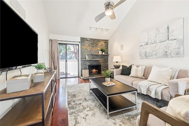 living area with track lighting, a fireplace, a ceiling fan, and wood finished floors