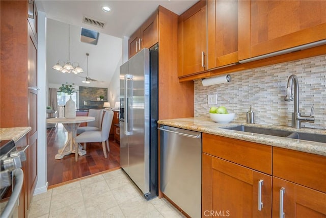 kitchen featuring light stone counters, brown cabinets, appliances with stainless steel finishes, and a sink