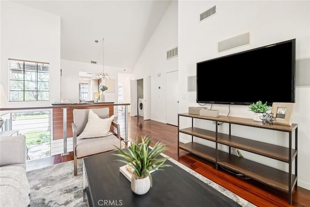 living area featuring visible vents, high vaulted ceiling, independent washer and dryer, and wood finished floors