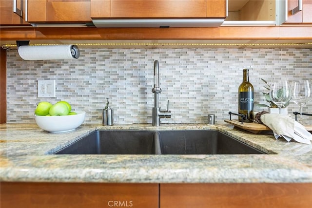 details with a sink, decorative backsplash, and light stone counters