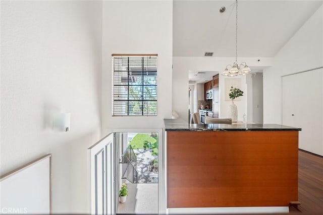 kitchen with visible vents, dark wood-type flooring, dark countertops, and an inviting chandelier