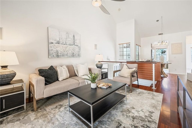 living room with baseboards, high vaulted ceiling, ceiling fan, and wood finished floors