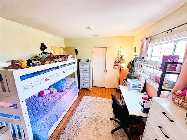 bedroom with light wood-style flooring, visible vents, and a closet