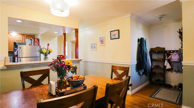 dining space with wood finished floors, baseboards, and ornamental molding