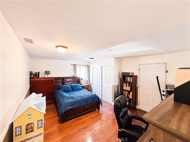 bedroom featuring a closet, visible vents, baseboards, and wood finished floors