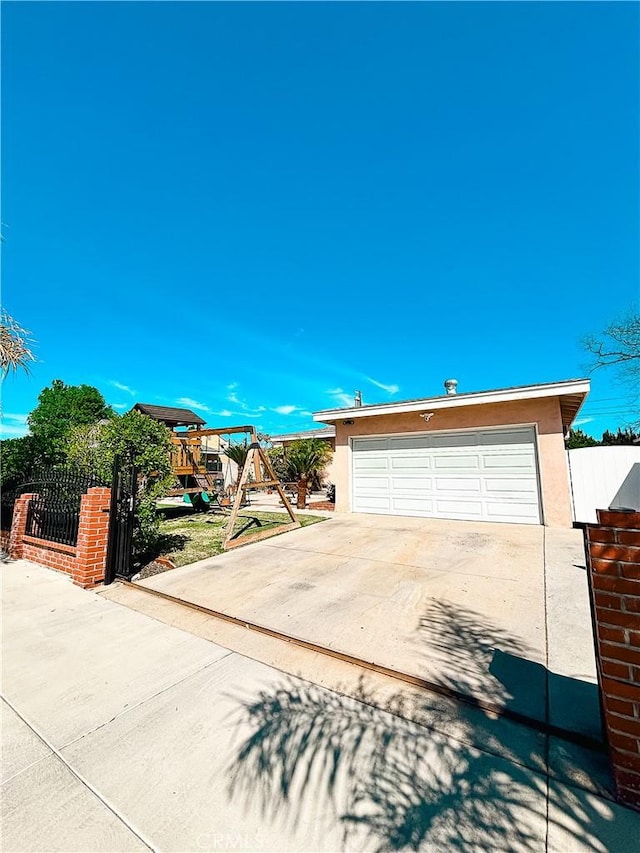 view of front of home with stucco siding, fence, a playground, concrete driveway, and a garage