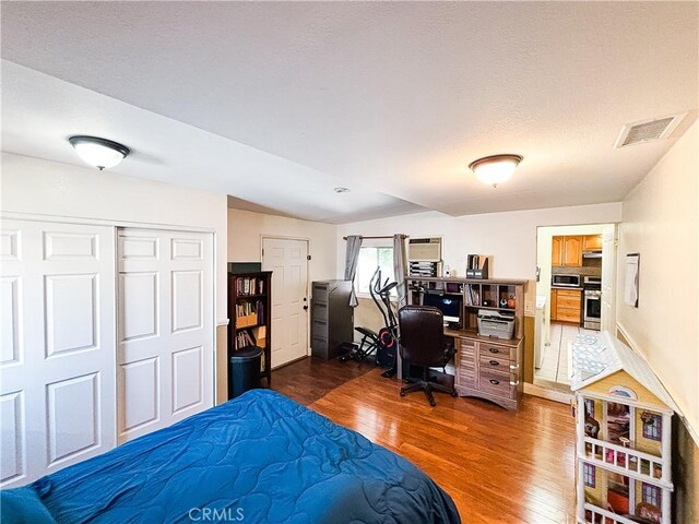 bedroom featuring visible vents, lofted ceiling, a closet, dark wood-style floors, and a textured ceiling