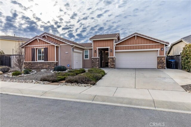 craftsman house featuring stone siding, concrete driveway, a garage, and fence