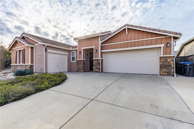 view of front of property with board and batten siding, concrete driveway, a garage, and stone siding