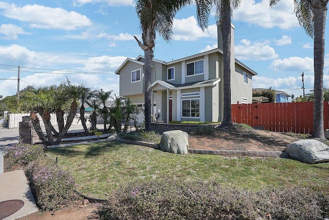 view of front of property featuring stucco siding, a front yard, and fence